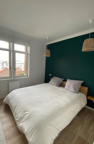 un grand lit blanc dans une chambre avec un mur vert dans l'établissement Christophe, à Le Touquet-Paris-Plage