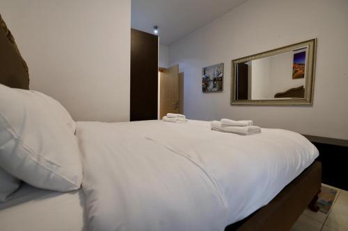 una camera da letto con un grande letto bianco con uno specchio di Sliema 2bed with Backyard a Sliema