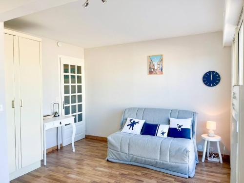 Una sala de estar con un sofá y un reloj en la pared. en Arthur, en Le Touquet-Paris-Plage