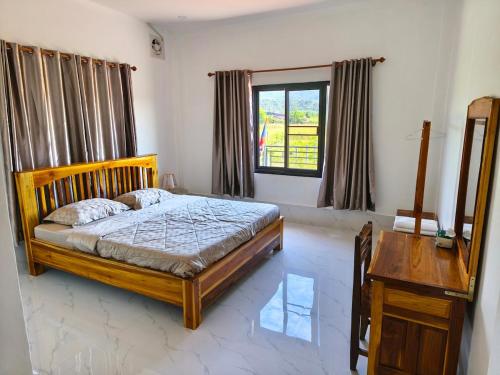 ein Schlafzimmer mit einem Bett und einem Tisch und einem Fenster in der Unterkunft Vang Vieng Cozy Villa in Vang Vieng