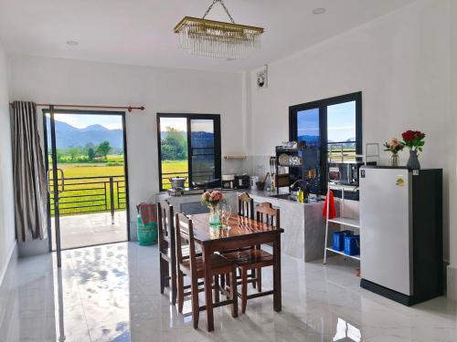eine Küche mit einem Tisch mit Stühlen und einem Kühlschrank in der Unterkunft Vang Vieng Cozy Villa in Vang Vieng