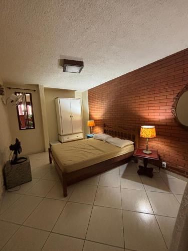 a bedroom with a bed and a brick wall at Casa Confortável - Cabo Frio in Cabo Frio
