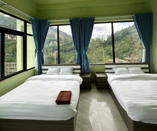 two beds in a room with large windows at Placement For Cloud Hunting in Suy Tung Su
