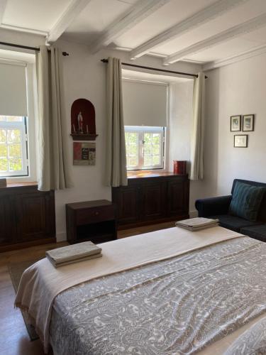 a bedroom with a large bed and two windows at Casa Morgado do Casco in Estremoz