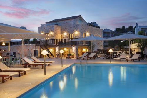 una piscina de hotel con sillas y sombrillas y un edificio en Thirides Beach Resort, en Gythio