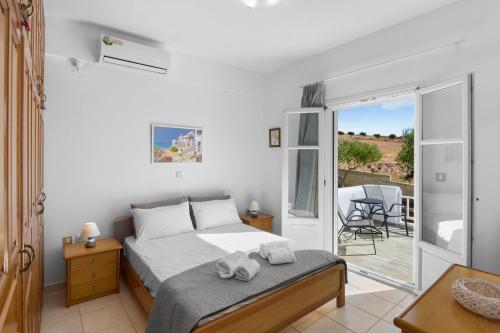 Un dormitorio con una cama y un balcón con una mesa. en Anthoula's Sea View Apartment, en Piso Livadi