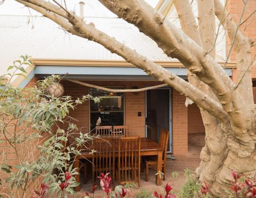 a house with a wooden table and a tree at Middleton Beach Abode in Albany