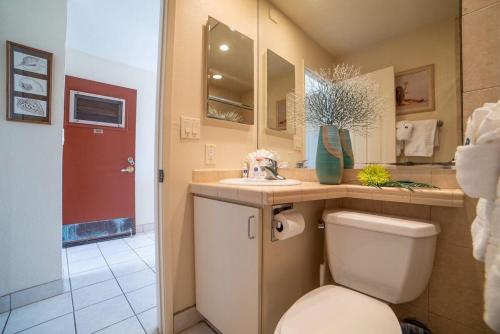 a bathroom with a toilet and a sink and a red door at Kulakane 105 · KK105 Sunsets Ocean Views Oceanfront in West Maui in Kahana