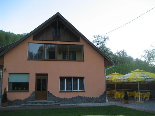 a house with tables and umbrellas in front of it at Pensiunea Colt Alb in Băile Homorod