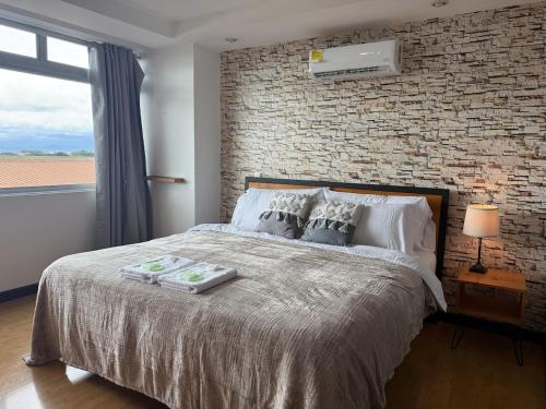 Un dormitorio con una cama grande con una pared de ladrillo. en Peaceful Escazu Getaway with Pool, Wi-Fi & Work Space, en Santa Ana