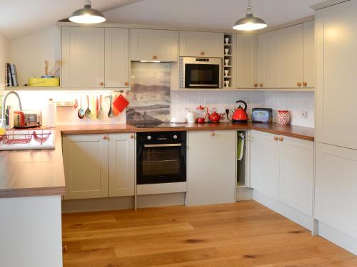 a kitchen with white cabinets and a stove top oven at The Byre in Rispond
