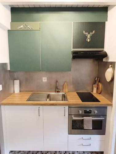 a kitchen with white cabinets and a sink at Chez Cle'Montagne in Ovronnaz