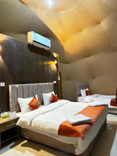 a bedroom with two beds and a tv on the wall at Rum Paradise luxury camp in Wadi Rum