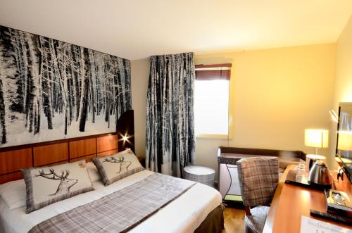 a bedroom with a bed and a desk and a window at Green hotels Confort Paris 13 in Paris