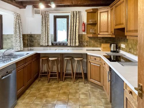 バンプトンにあるDuvale Barnの木製キャビネットとバースツール付きの広いキッチン