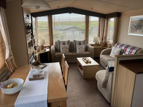 a living room with a couch and a table at Caravan by Sea in Morfa Nefyn