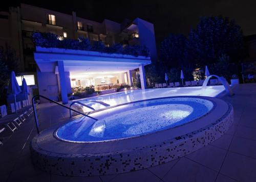 a jacuzzi tub in front of a building at night at Hotel Byron in Rimini