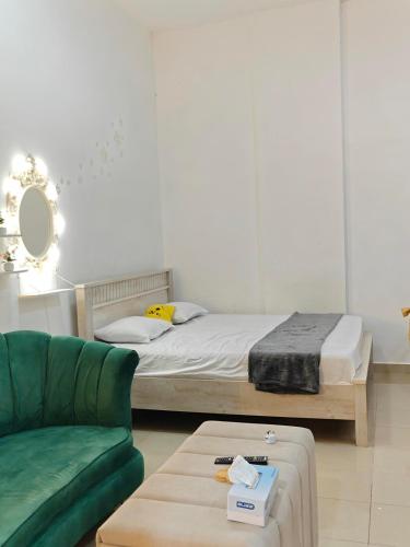 Un dormitorio con una cama y un sofá verde. en Studio Available in MBZ Abu Dhabi, en Abu Dabi