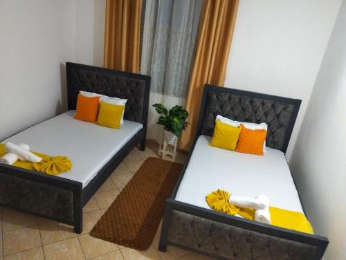 ディアニ・ビーチにあるPalm Beach Apartmentsのオレンジと黄色の枕が備わる客室のベッド2台