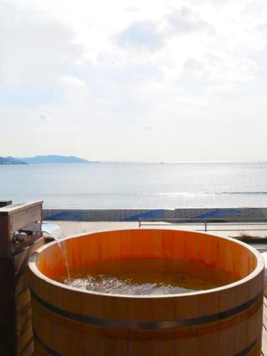 a large barrel with water in it next to the ocean at mokumoku海sakanoshita in Kamakura