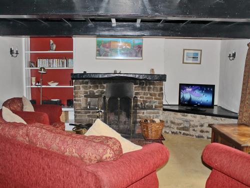 a living room with two red couches and a fireplace at Elm Cottage in Beckermonds