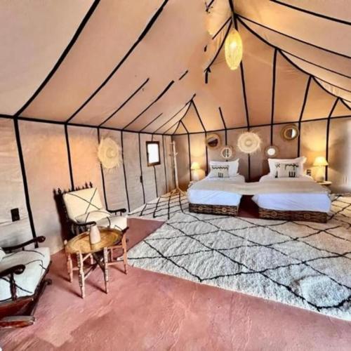 a room with two beds and a table in a tent at Ahlam luxury camp in Merzouga