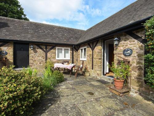 a stone cottage with a table in the courtyard at The Old Barn in Hope Bowdler