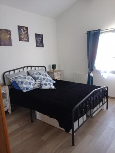 a bedroom with a bed with a black blanket and a window at Charmante Maison Bord de Mer avec Piscine et Tennis 5-P in Saint-Vincent-sur-Jard