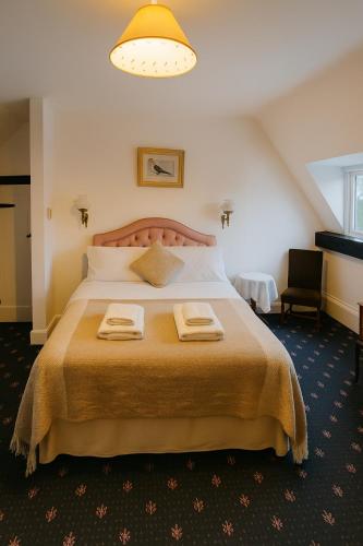 a bedroom with a large bed with two towels on it at 4 Bed Cottage with Hot Tub near Wyboston Lakes in Wyboston