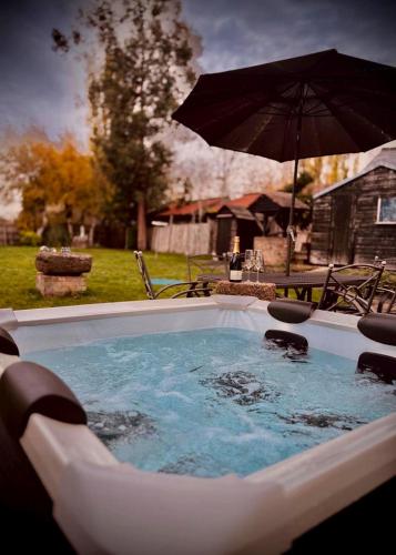 a hot tub with an umbrella in a yard at 4 Bed Cottage with Hot Tub near Wyboston Lakes in Wyboston