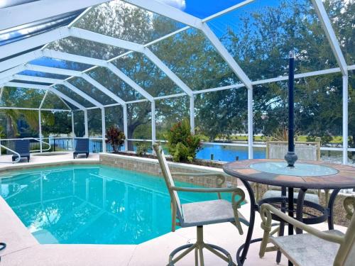 einen Pool mit einer Pergola, einem Tisch und Stühlen in der Unterkunft Waterfront VILLA with heated Pool&Spa, sunset view, Family&Pets Friendly in Cape Coral