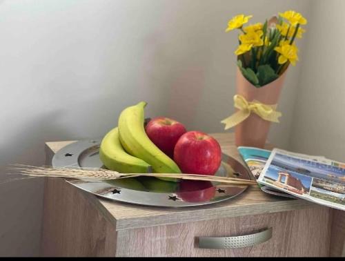 une assiette de fruits sur une table avec des pommes et des bananes dans l'établissement Nissi Pearl villa close Nissi beach, à Ayia Napa