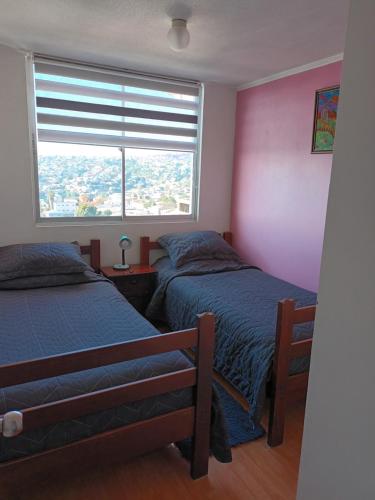two beds in a room with a window at Hospedaje en departamento compartido in Valparaíso
