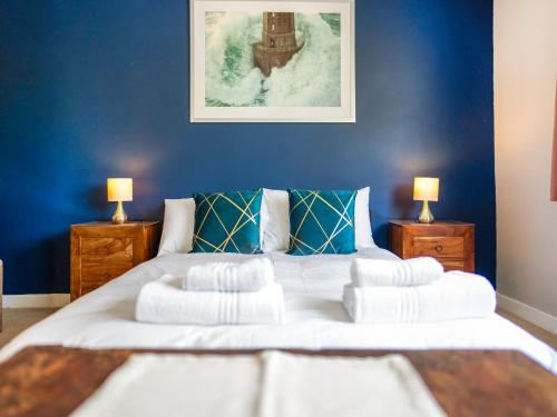 een slaapkamer met een groot wit bed met blauwe muren bij Applepips in Stirling