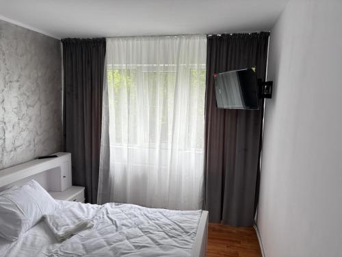 a bedroom with a bed and a television on a wall at Apartament Lux 3 camere in Roman