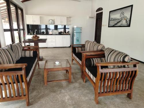 a living room with couches and a table and a kitchen at Samudura Beach House, Owakanda in Rathgama