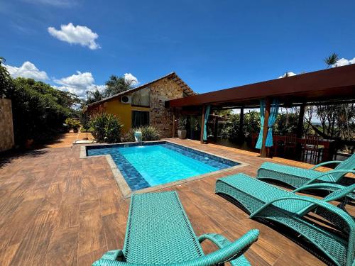 ein Swimmingpool mit grünen Stühlen und einem Haus in der Unterkunft Rancho Flor de Iris - Lago Corumbá IV in Alexânia