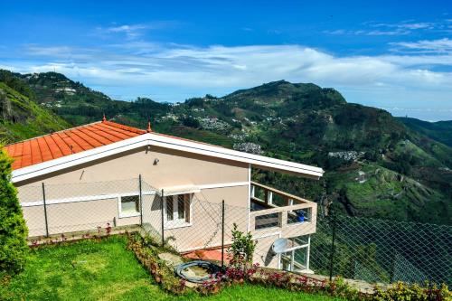 une maison sur une colline avec des montagnes en arrière-plan dans l'établissement Syamantac Villa, à Kodaikānāl