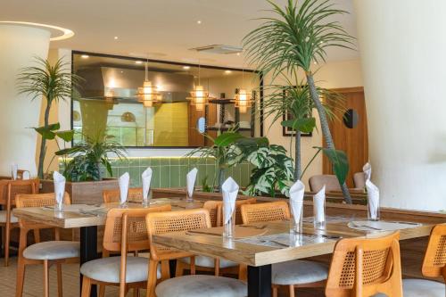Un restaurante con mesas y sillas de madera y plantas. en Waterfront Villas And Wellness SPA, en Warri