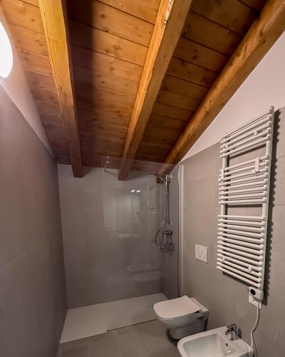 a bathroom with a white toilet and a wooden ceiling at B&B Battista in Sacile