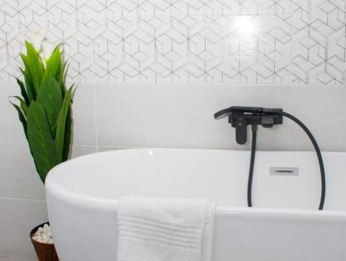 RandfonteinにあるGuesthouse in Randfonteinの白いバスタブ(蛇口、植物付)