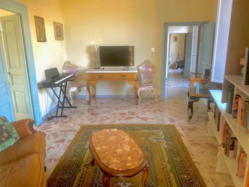 ein Wohnzimmer mit einer Couch und einem Schreibtisch mit einem Fernseher in der Unterkunft Casa Abenante in Corigliano Calabro