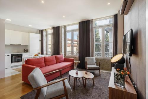 a living room with a red couch and a kitchen at Bracara Home By Minhos Guest in Braga