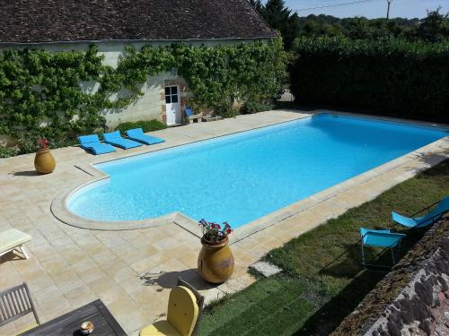 a large swimming pool with blue chairs in a yard at Tourterelle, à proximité de Auxerre et Chablis in Hauterive
