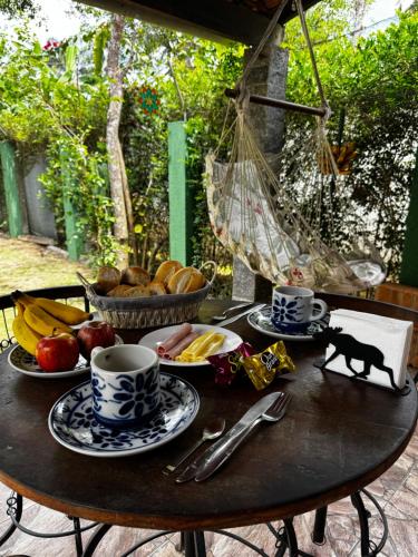 een tafel met bekers en borden met voedsel erop bij Suíte penedo in Itatiaia
