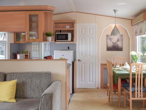 a kitchen and living room with a table and chairs at Tranquillity Lodge in Annbank