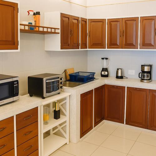 a kitchen with wooden cabinets and a microwave at Guest house La Casa del Quetzal in Mérida