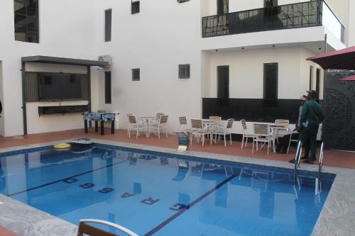 a man is standing next to a swimming pool at Grabbo Luxury Apartments in Gwarinpa