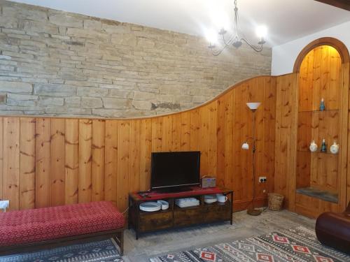 een woonkamer met houten wanden en een televisie bij Detached cottage in town, Spacious rustic charm in Lindley