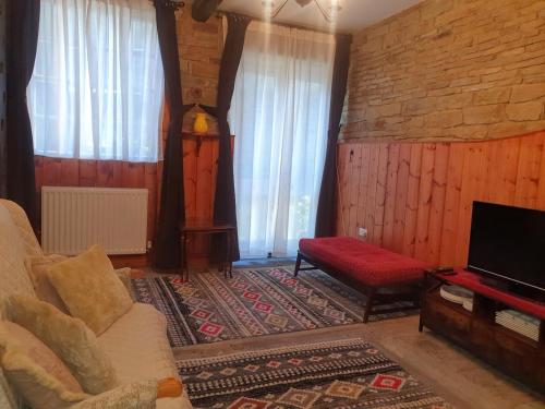 een woonkamer met een bank en een tv bij Detached cottage in town, Spacious rustic charm in Lindley